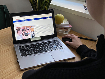 Eine Person betrachtet auf ihrem Laptop die Website der Universität.